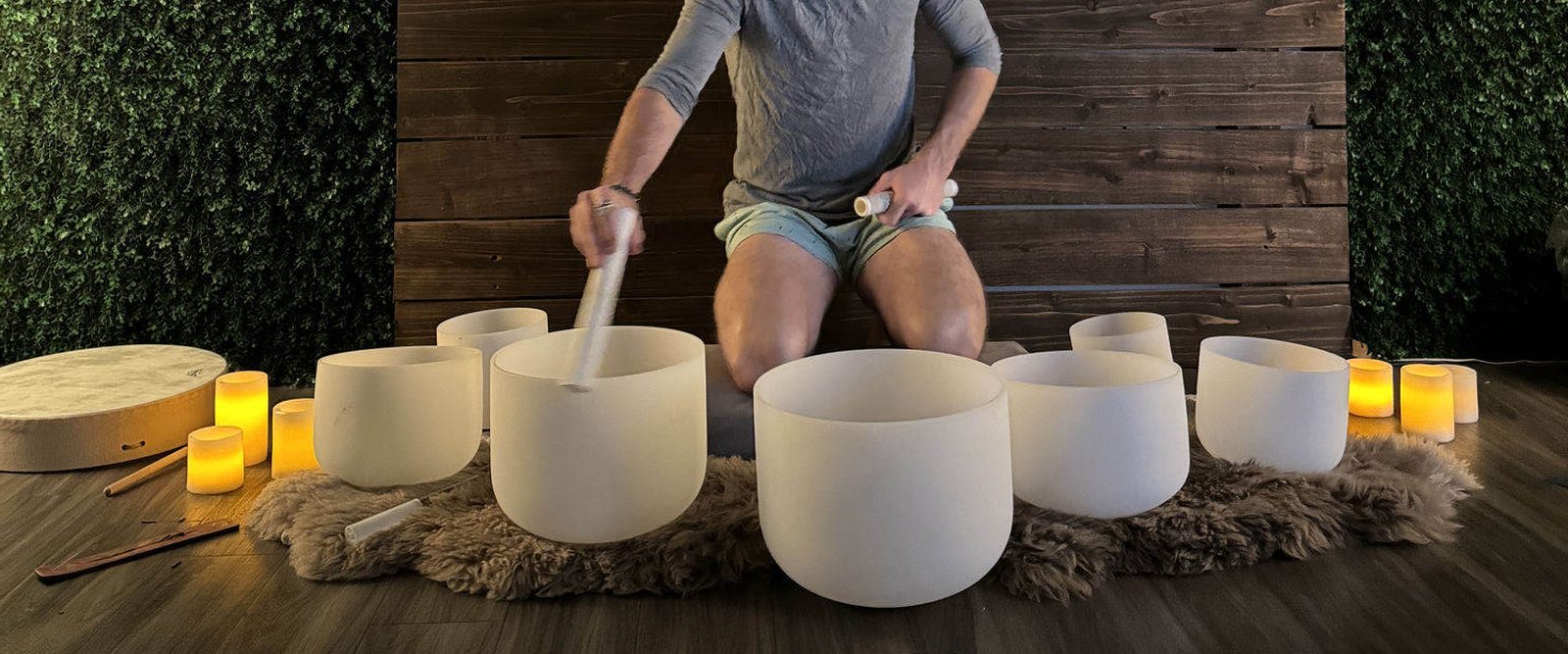 Xander playing a row of crystal singing bowls by candlelight