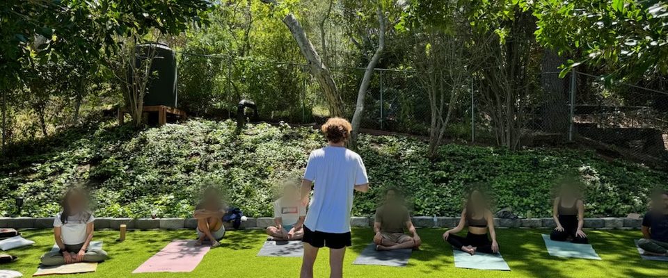 Xander leading an outdoor group class, students seated on mats