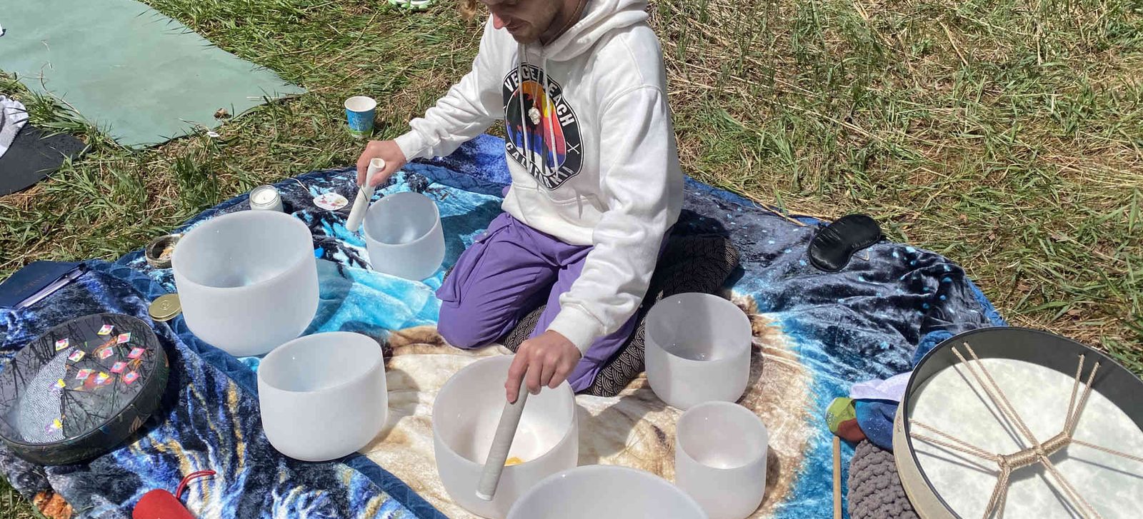 Xander playing singing bowls at an outdoor sound bath